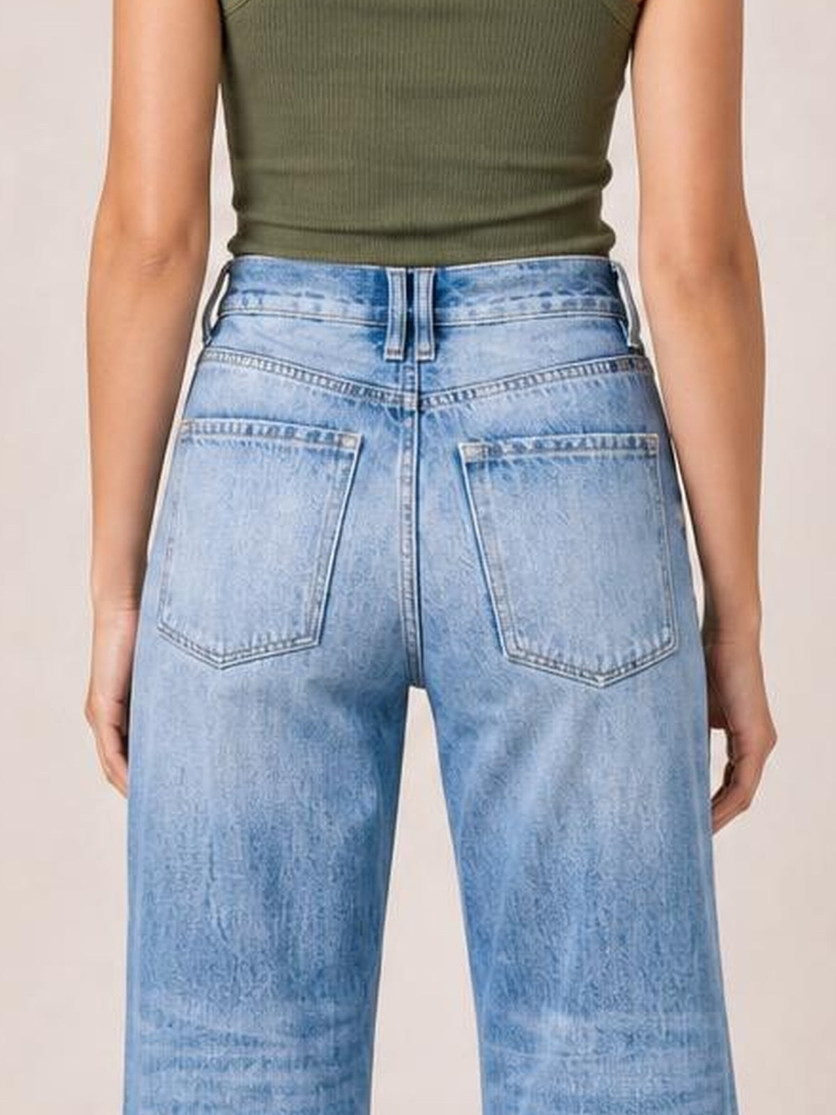 Back view of a model wearing light blue distressed straight leg jeans with a high-rise waistband, belt loops, contrast seams, and two large back pockets.