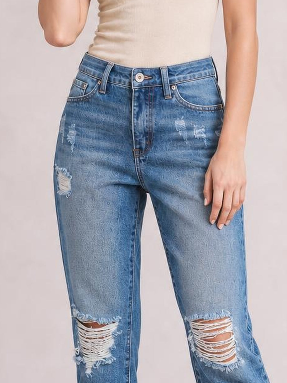 A model stands in light-blue distressed wash jeans with a structured waistband, belt loops, five-pocket construction, ripped knees, and a slim straight silhouette.