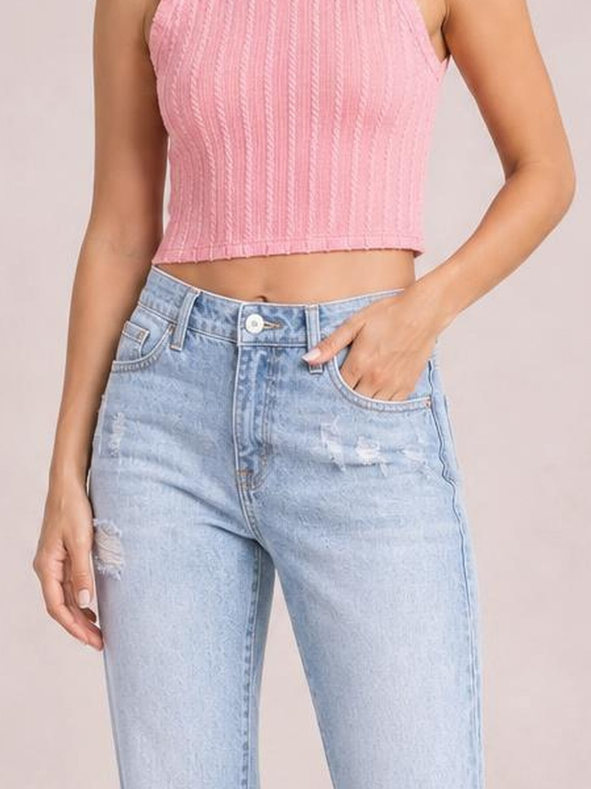 A model wears light-wash distressed jeans with a high-rise straight-leg silhouette, belt loops, button closure, front pockets, and one hand tucked inside.