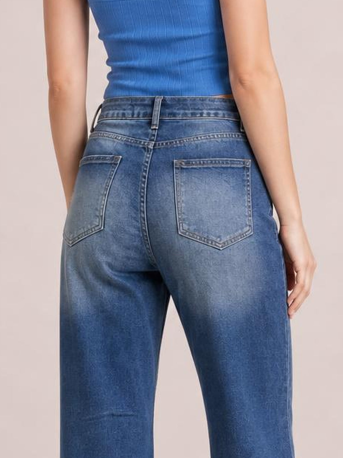 Model shown from behind wearing blue distressed wide-leg jeans with a high-rise waistband, belt loops, contrast stitching, and two back pockets.