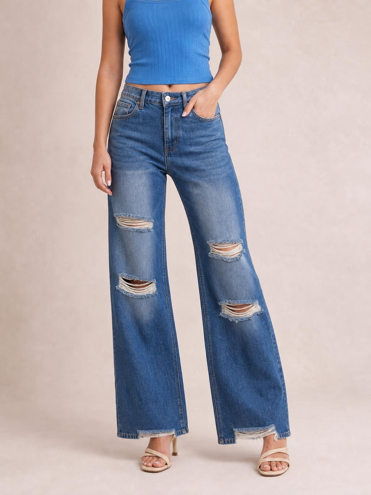 A model wears blue distressed wide leg jeans with a high waist, button closure, front pockets, frayed knee and hem details, and a relaxed silhouette.
