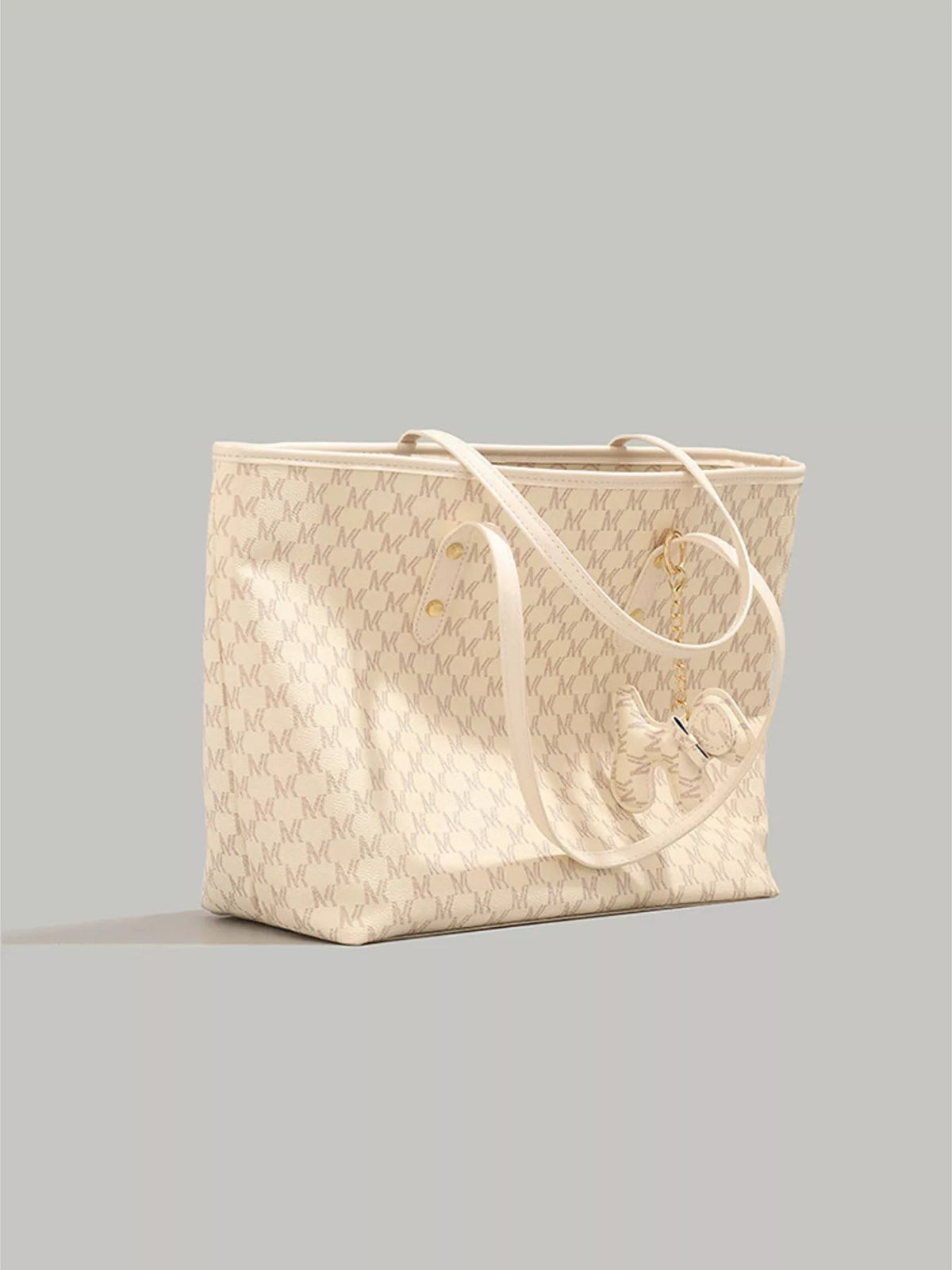 Large cream PU leather tote bag with a repeating monogram pattern, double shoulder straps, and a gold-tone chain dog charm with a bow detail.