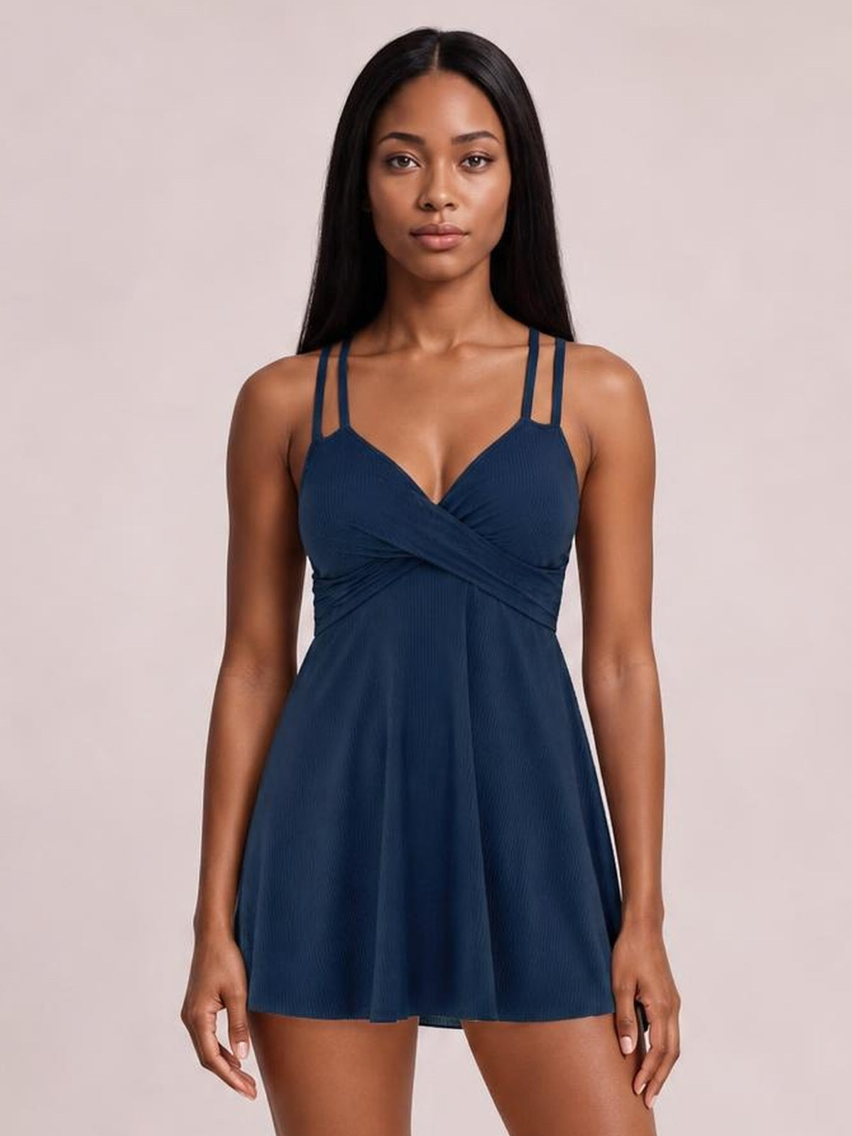A model stands front-facing in a navy Double-Strap Cutout Swim Dress with a plunge neckline, crossed ruched bodice, and softly flared skirt silhouette.