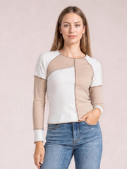 Model wearing a fitted color block ribbed top with exposed seams, white and taupe panels, long sleeves, and a defined vertical center seam.