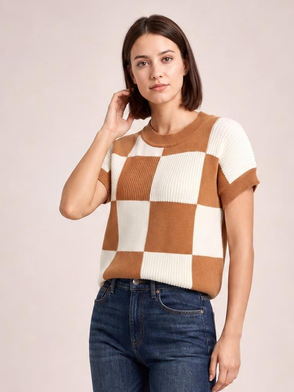 Model wearing a brown and cream checkered round neck short sleeve sweater with ribbed trim and a relaxed, slightly cropped silhouette.