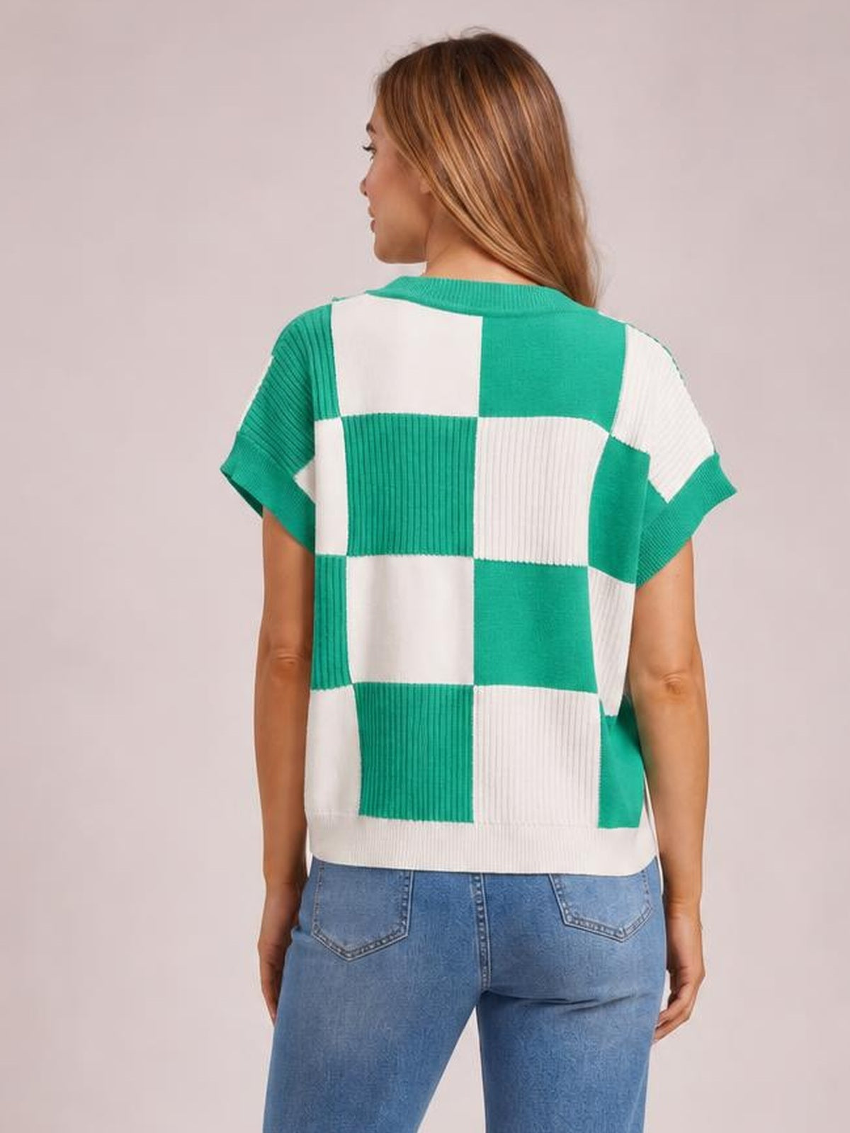 A model is shown from behind wearing a green and white checkered round-neck short-sleeve sweater with a relaxed silhouette and ribbed knit construction.
