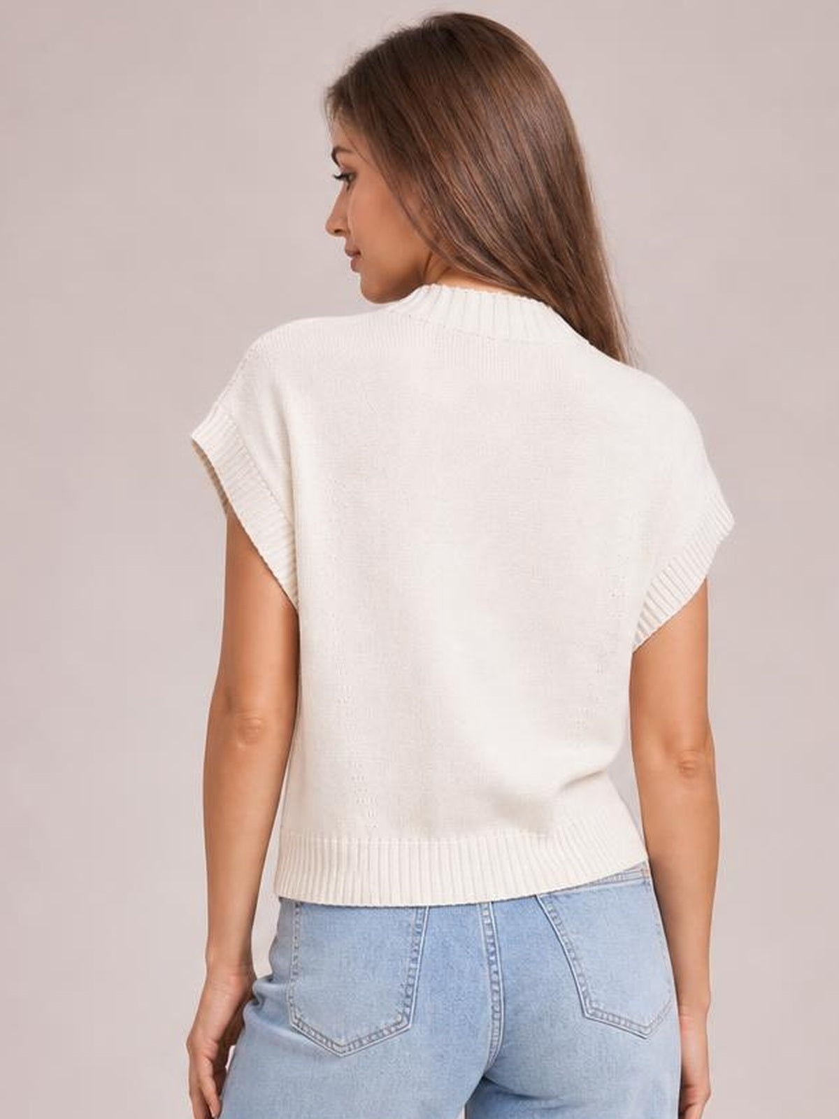 Back view of a model wearing a white mock neck short sleeve sweater with a relaxed silhouette, ribbed sleeve cuffs and hem, standing with hands at her sides.