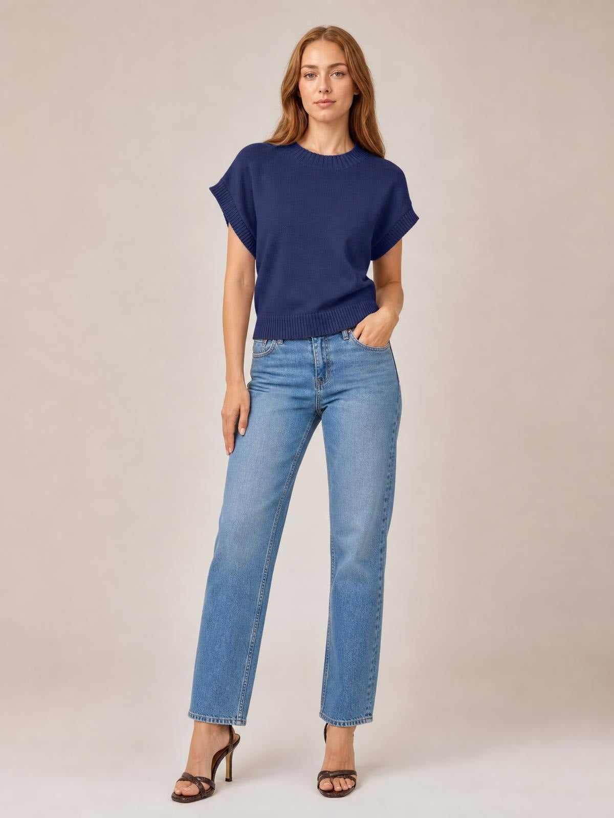 Model poses in a navy mock neck short sleeve sweater with a relaxed boxy silhouette, ribbed neckline, sleeve cuffs, and hem.