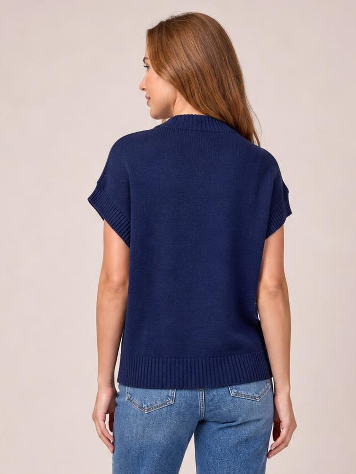 A model shows the back of a navy mock neck short sleeve sweater with ribbed collar, cuffs, and hem in a relaxed, straight silhouette.