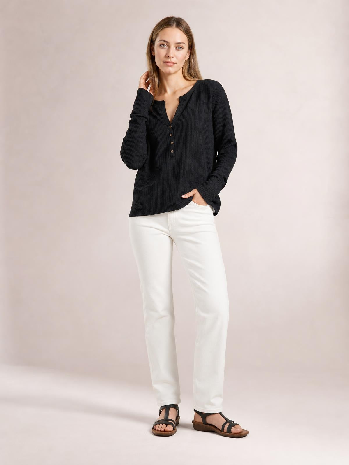 Model wearing a black notched thumbhole long sleeve T-shirt with a relaxed silhouette, textured fabric, and buttoned front placket.
