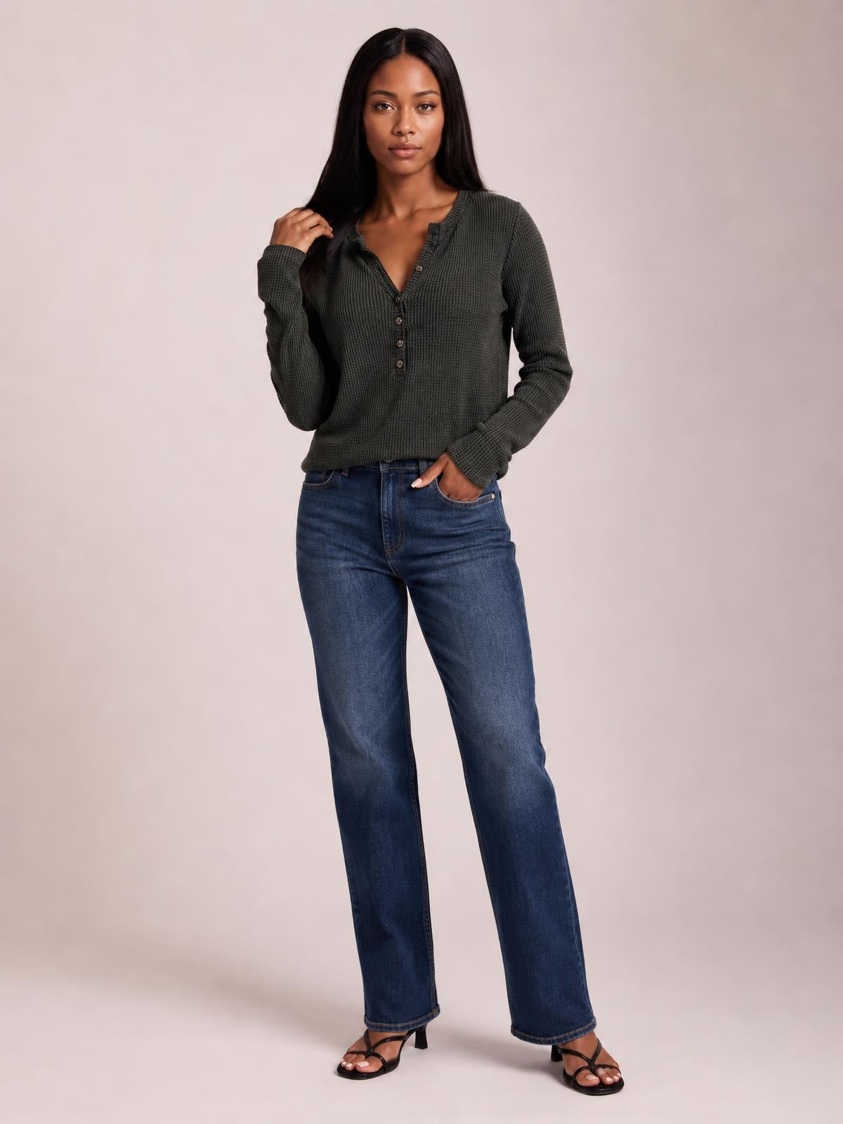 A model poses in a dark charcoal notched thumbhole long sleeve T-shirt with a textured knit, buttoned V-neck placket, and relaxed silhouette.