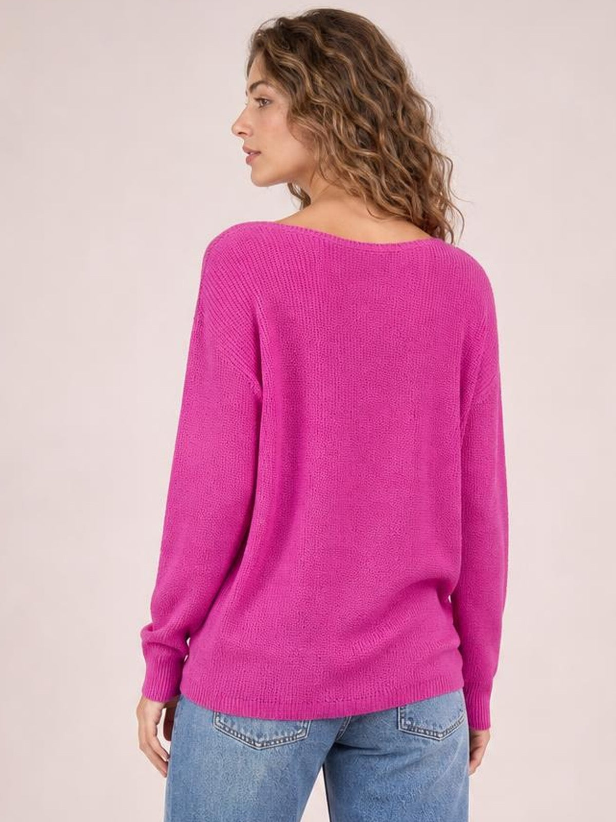 Model shown from behind wearing a bright pink long sleeve T-shirt with a relaxed silhouette, wide neckline, ribbed cuffs, and a ribbed hem.