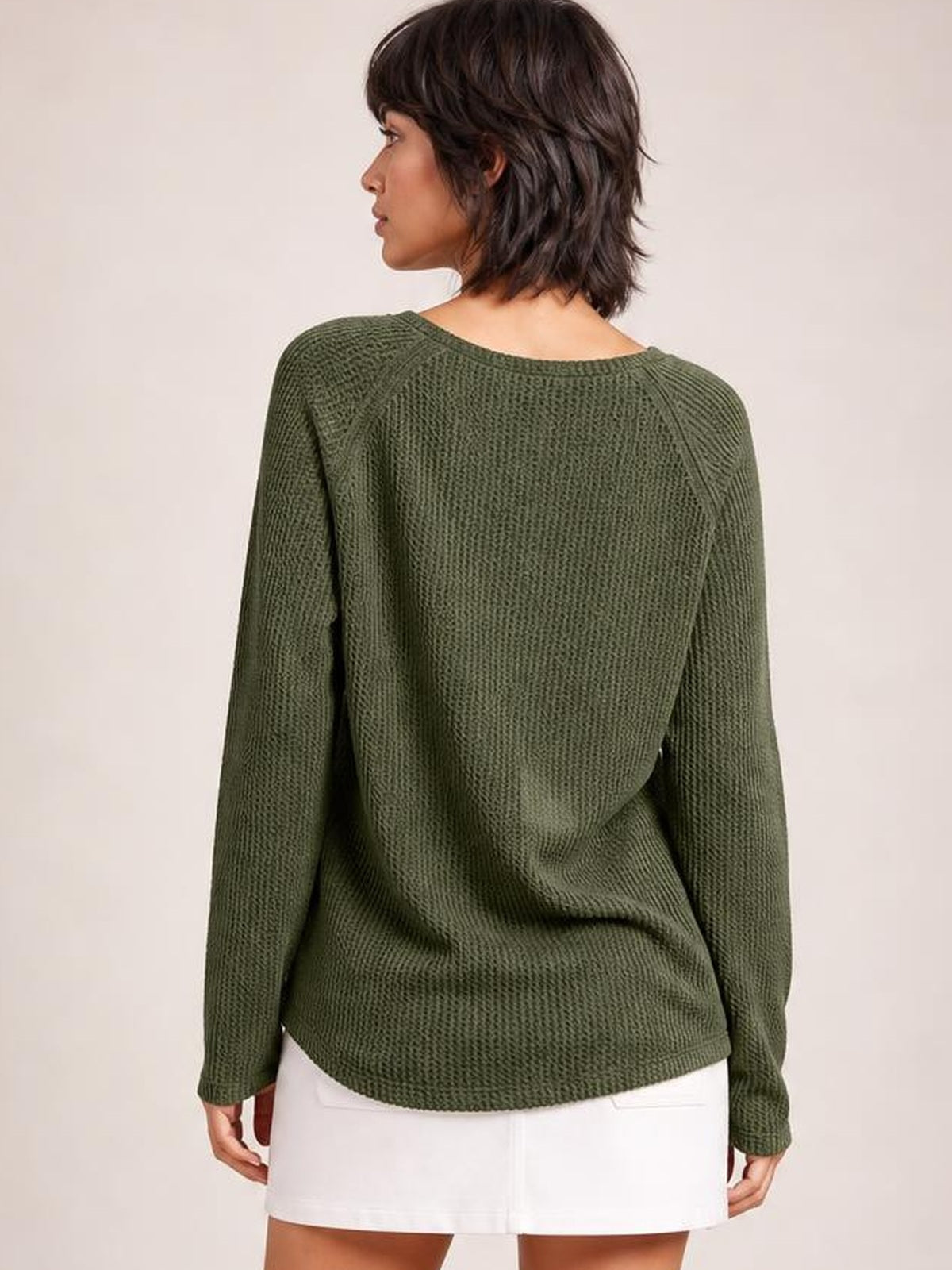 Model shown from behind wearing an olive green long sleeve T-shirt with a relaxed silhouette, textured knit construction, wide neckline, and raglan-style seams.