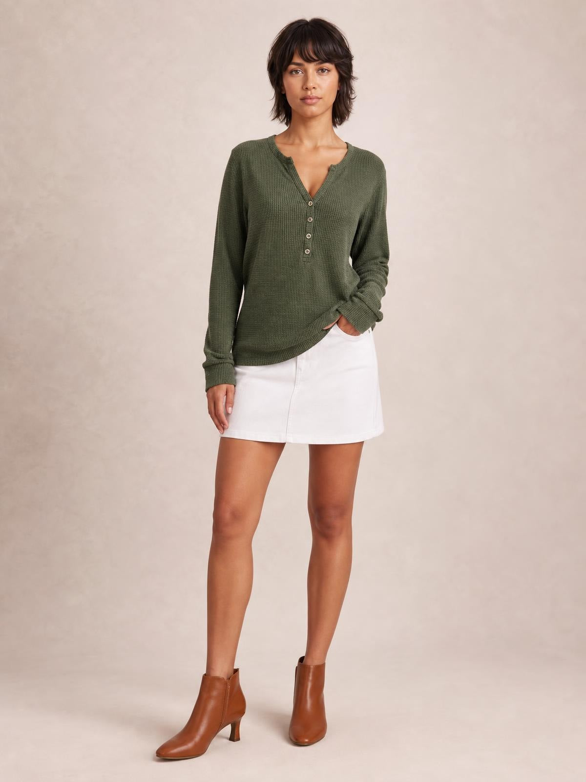 Model wears an olive green long sleeve T-shirt with a notched neckline, button details, ribbed texture, and a relaxed straight silhouette.