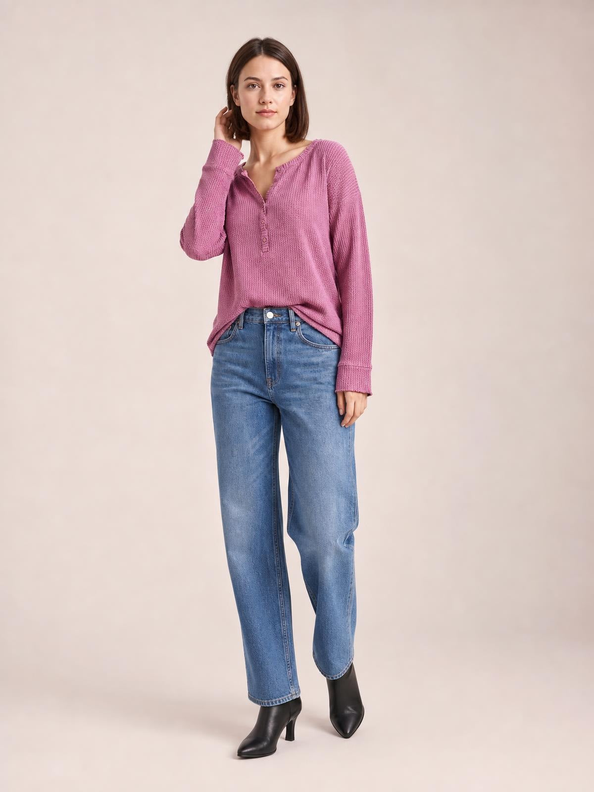 A model poses in a mauve long sleeve T-shirt with a notched neckline, button placket, textured construction, relaxed silhouette, and ribbed cuffs.