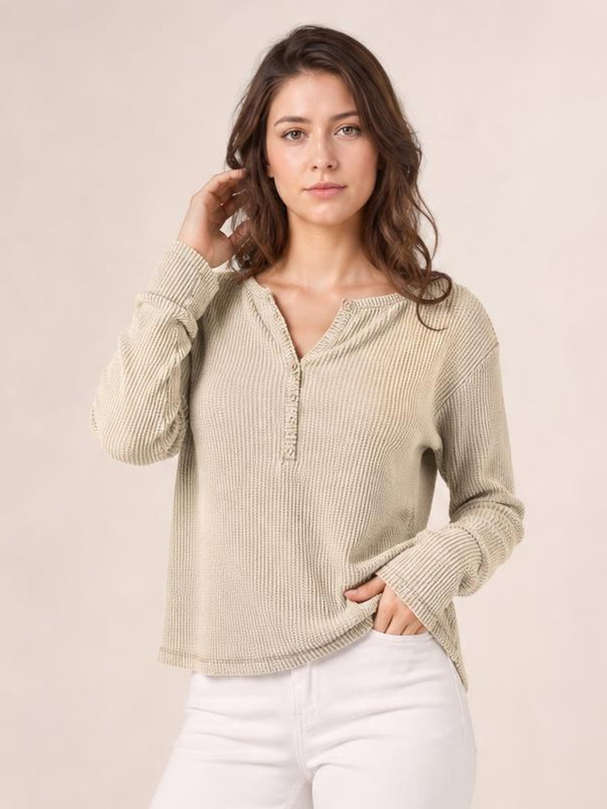 A model poses in an oatmeal notched thumbhole long sleeve T-shirt with a relaxed silhouette, waffle-knit texture, button placket, and extended cuffs.