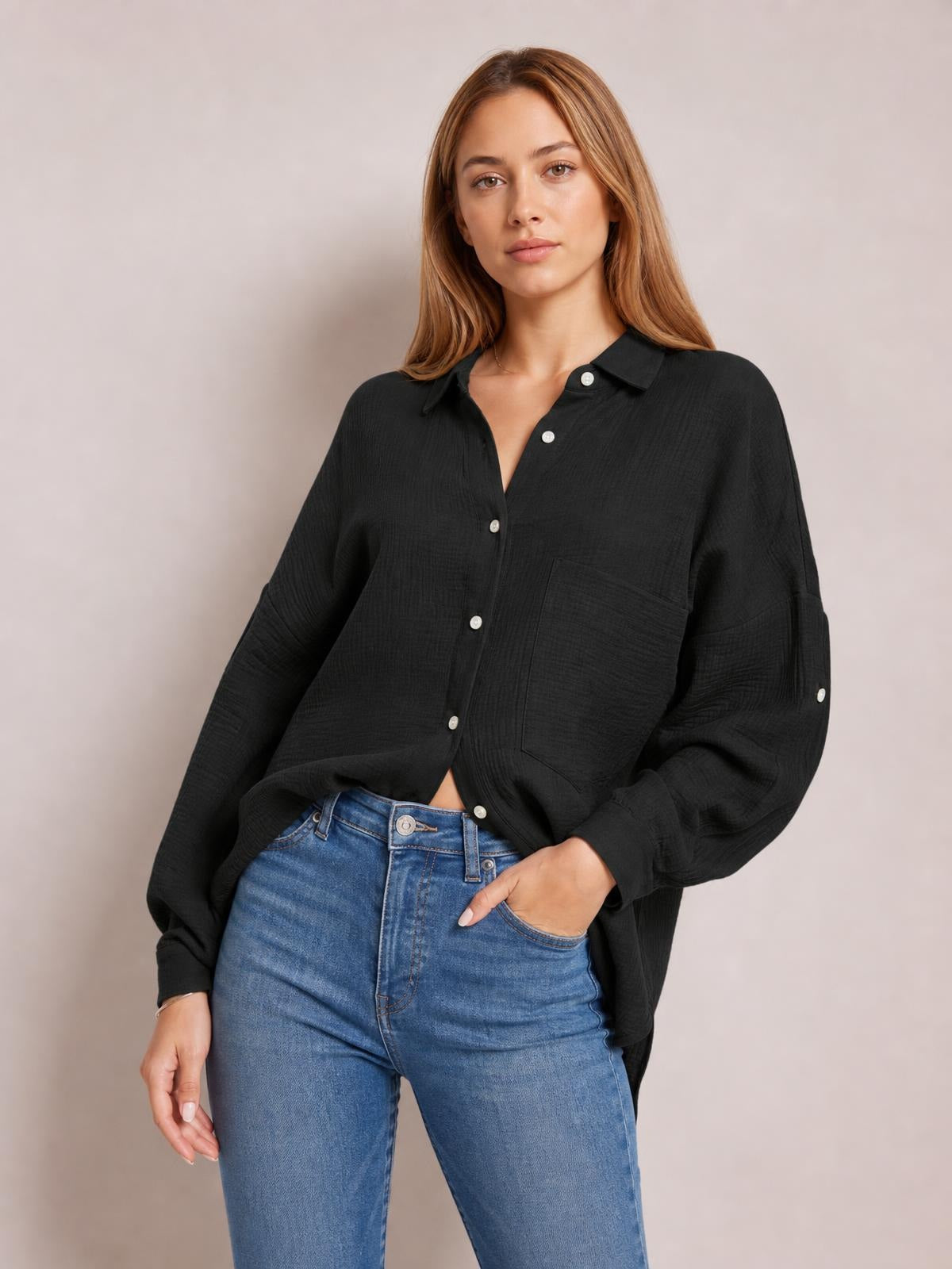 Model wears a black textured button-up shirt with a pointed collar, patch pocket, relaxed silhouette, long sleeves, and a slightly curved hem.