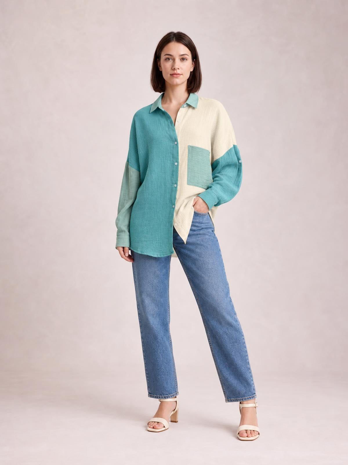 Model poses in a relaxed button-up shirt with a pointed collar, textured teal and cream color-blocking, long sleeves, front buttons, and a chest pocket.