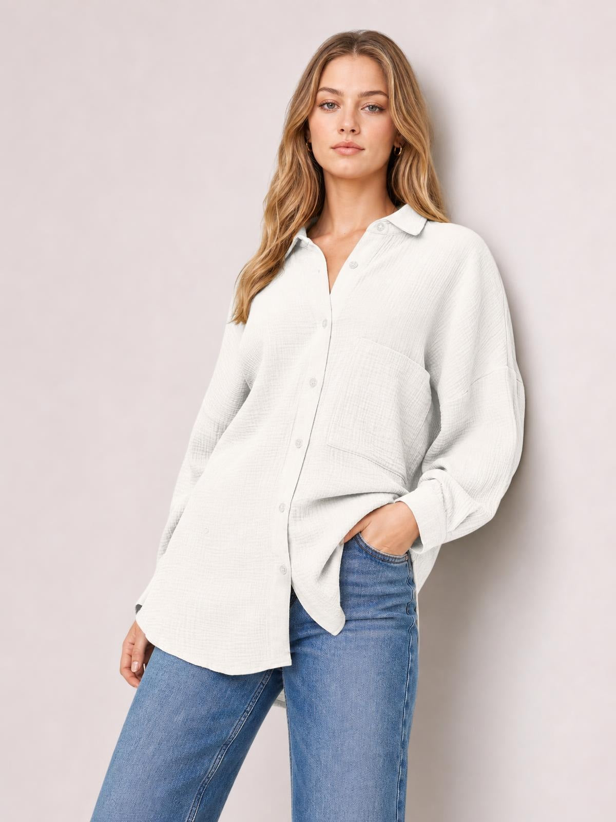 Model poses in a white textured button-up shirt with a collared neckline, front buttons, chest pockets, long sleeves, and a relaxed silhouette.