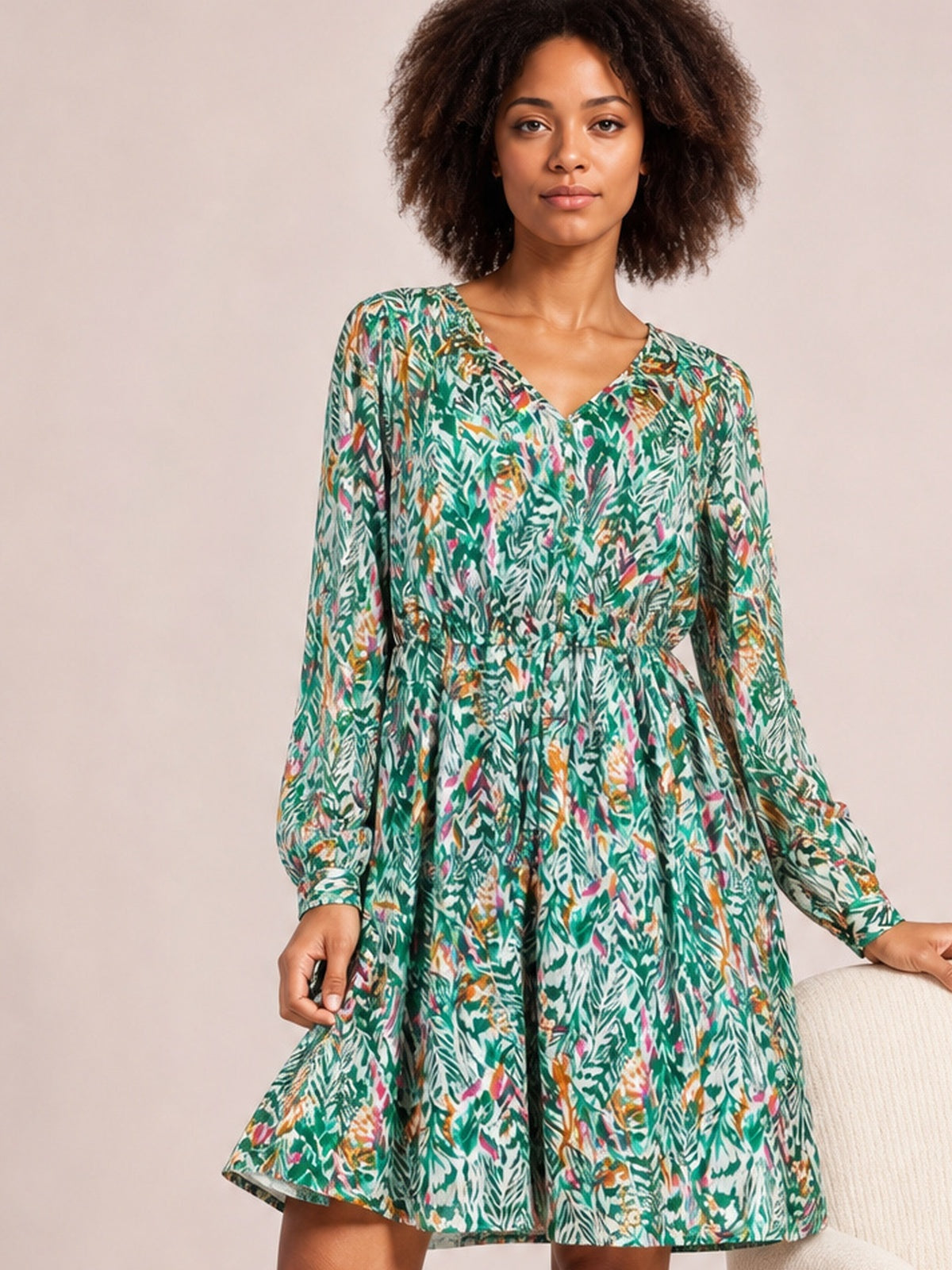 Model wears a green printed drawstring waist long-sleeve dress with a V-neck, ruched waist, and gently flared skirt while holding the hem.