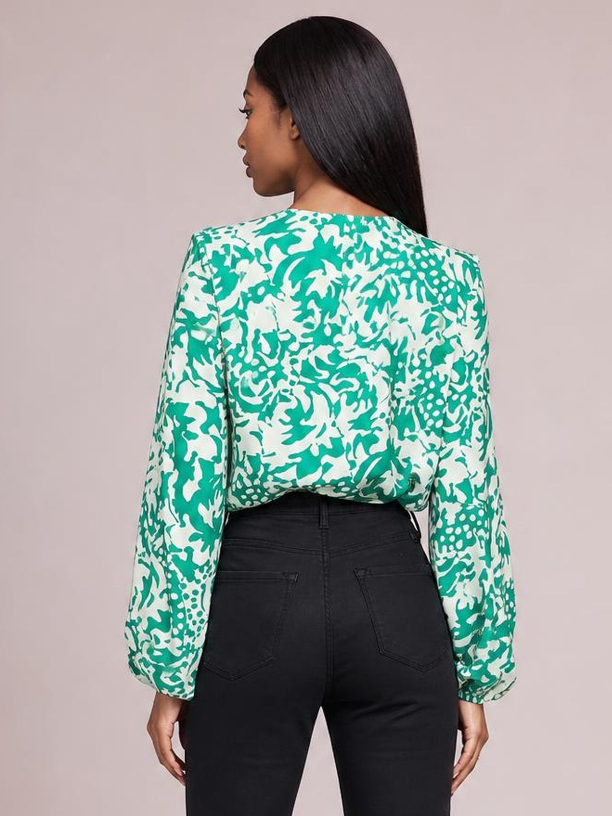 A model shown from the back wears a green-and-white printed shirt with voluminous balloon sleeves, a relaxed silhouette, and gathered cuffs.