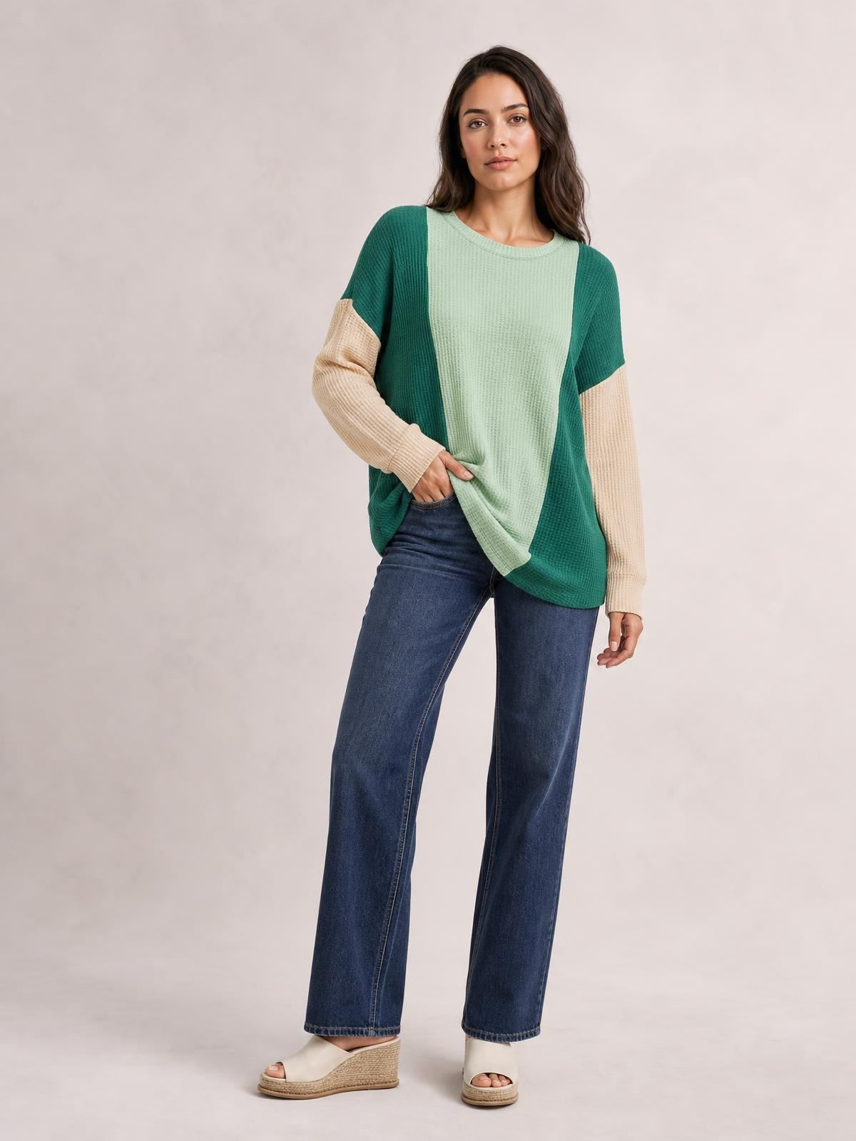 Model poses in a relaxed stance wearing a green and cream texture contrast round neck long sleeve T-shirt with a loose, slightly curved hem.