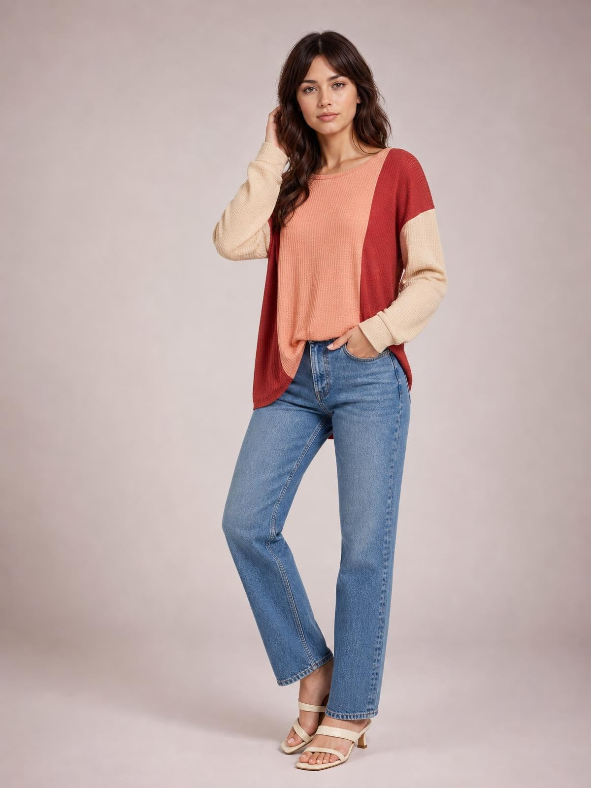 Model poses in a coral, burgundy, and cream texture-contrast round-neck long-sleeve T-shirt with a relaxed silhouette and curved hem.
