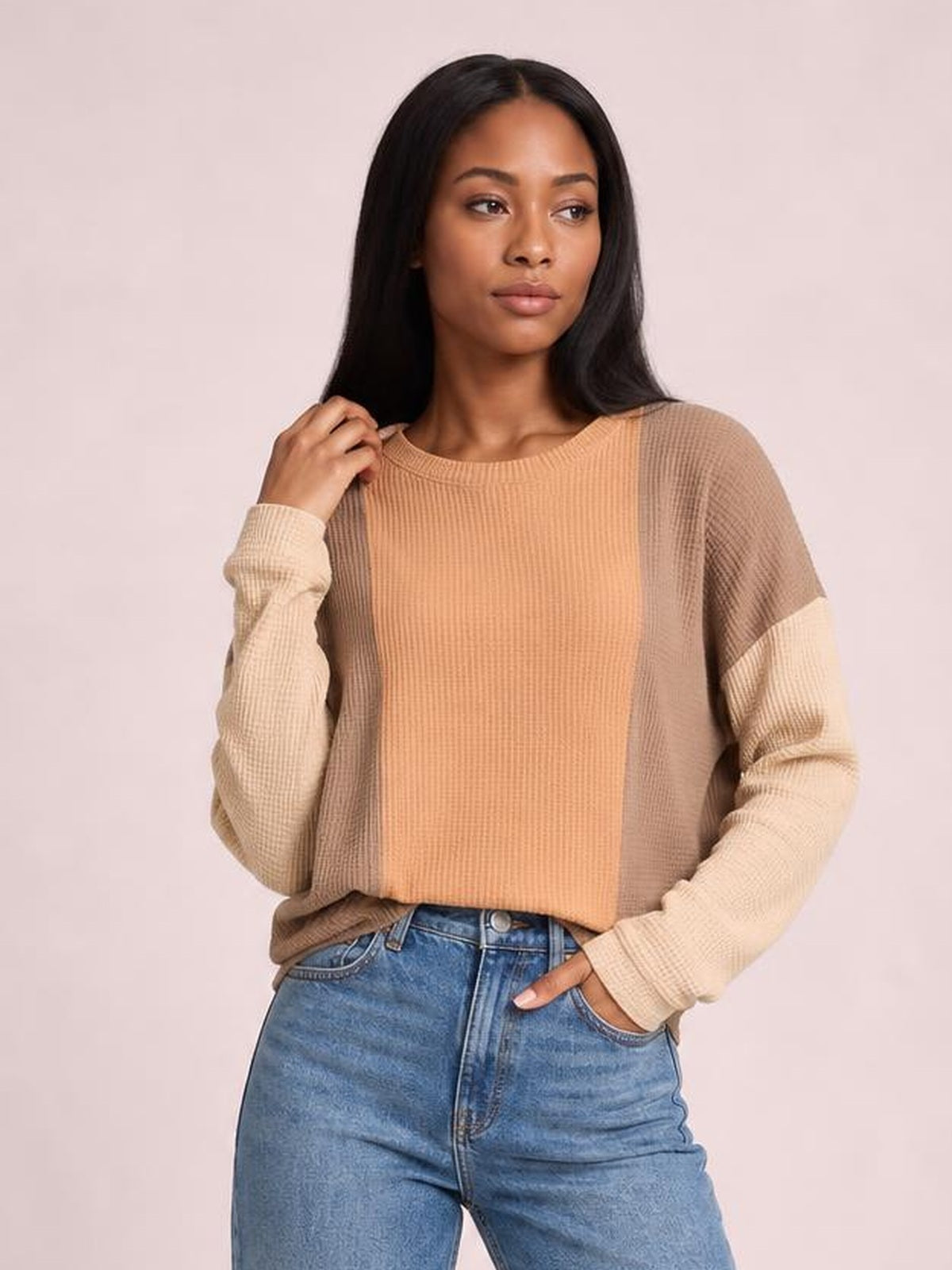 A model poses in a relaxed, slightly cropped texture contrast long-sleeve T-shirt with a round neck, ribbed tan body, and lighter color-blocked sleeves.