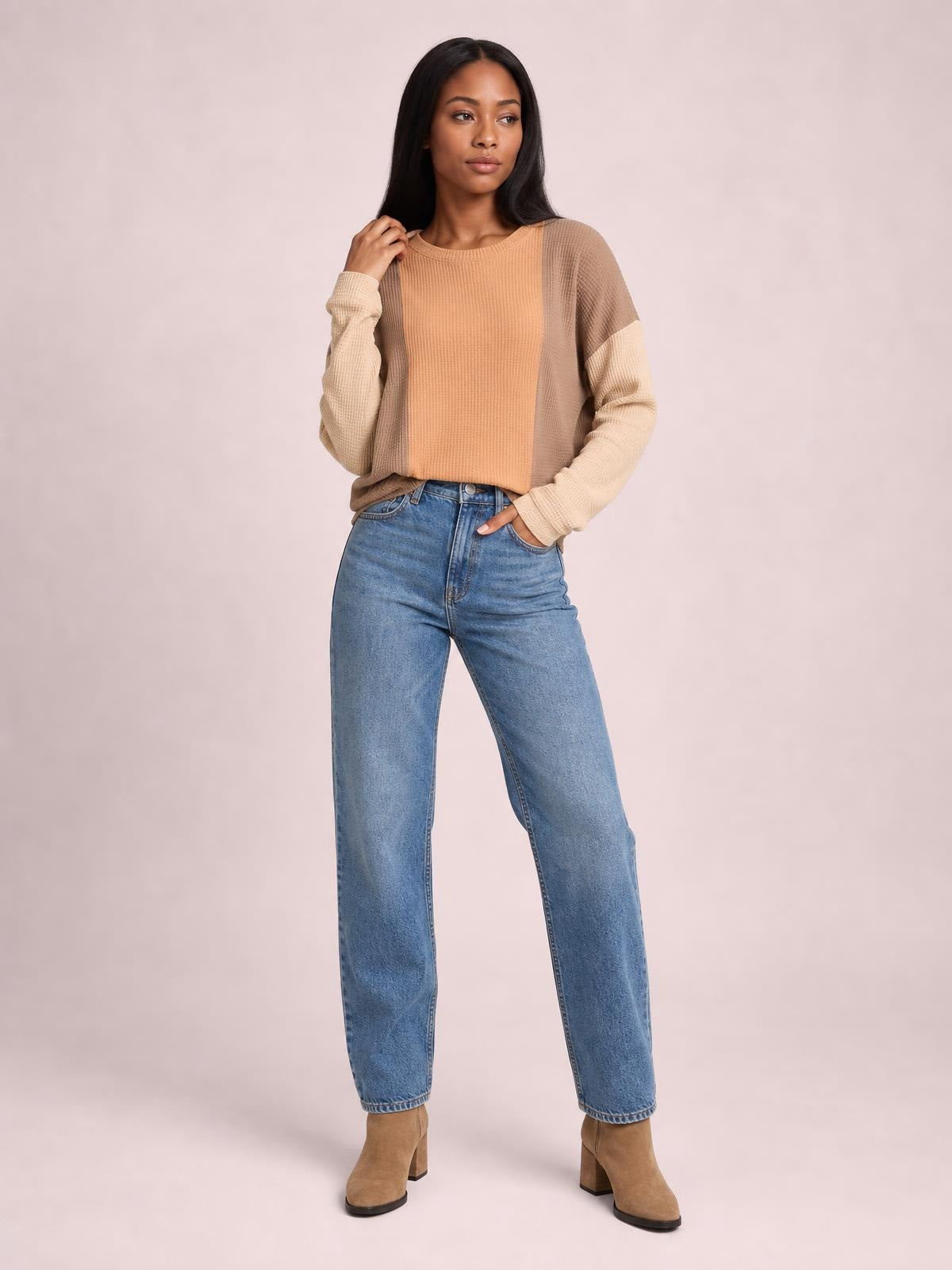 Model poses in a textured beige and tan contrast round-neck long-sleeve T-shirt with a relaxed silhouette, ribbed cuffs, and dropped shoulders.