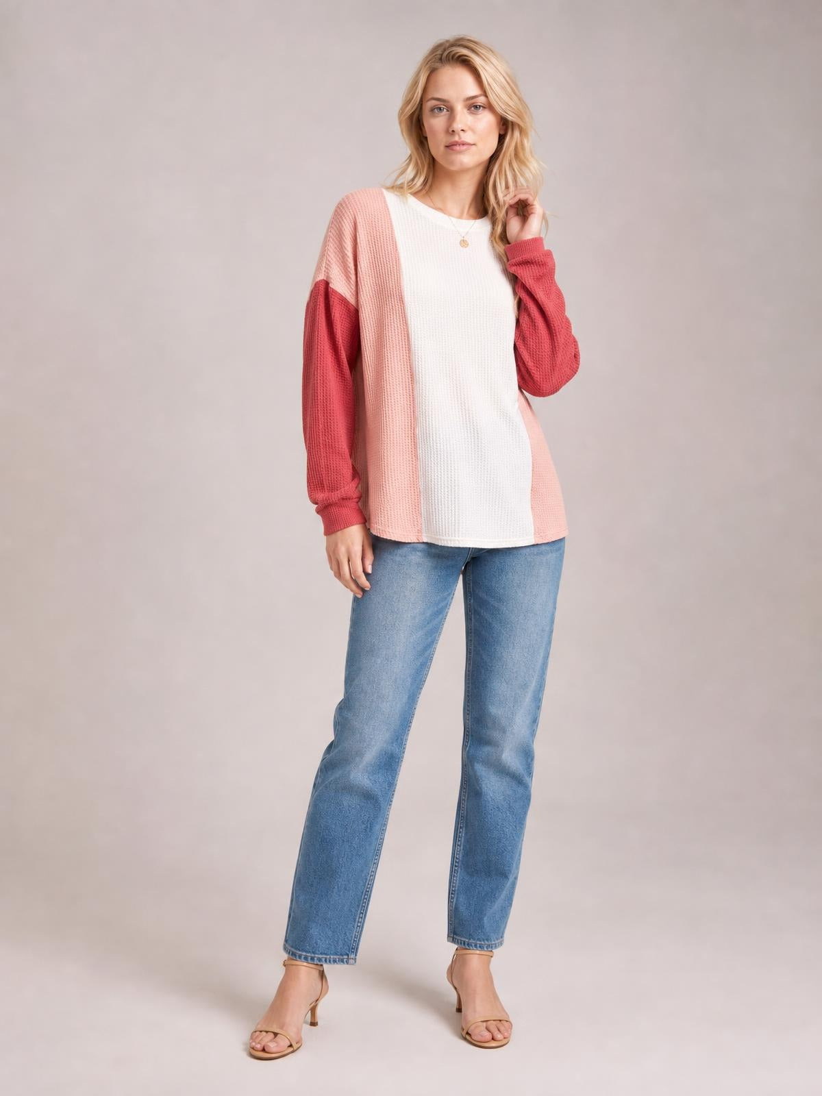 Model stands in jeans wearing a textured round-neck long-sleeve T-shirt with a white center, blush pink panels, and contrasting rose sleeves.