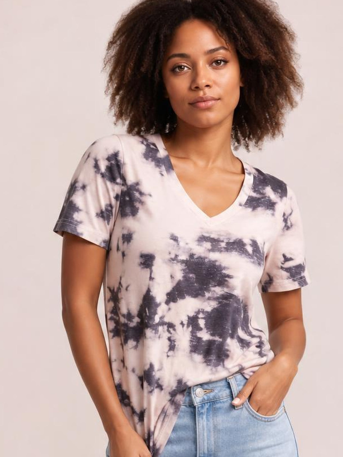 Model poses in a relaxed stance wearing an opaque tie-dye V-neck T-shirt with short sleeves, a soft white and dark gray pattern, and a casual straight silhouette.
