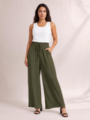 A model poses in olive green drawstring wide leg pants with a relaxed silhouette, elasticized waist, and front tie detail.