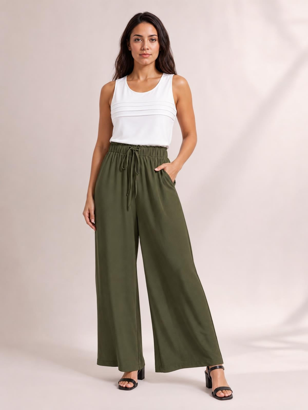 A model poses in olive green drawstring wide leg pants with a relaxed silhouette, elasticized waist, and front tie detail.