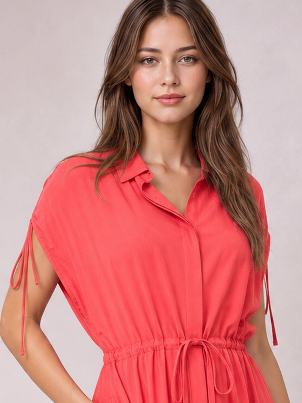 Model poses in a coral short-sleeve midi dress with a collared neckline, buttoned front, drawstring waist, and softly gathered silhouette.
