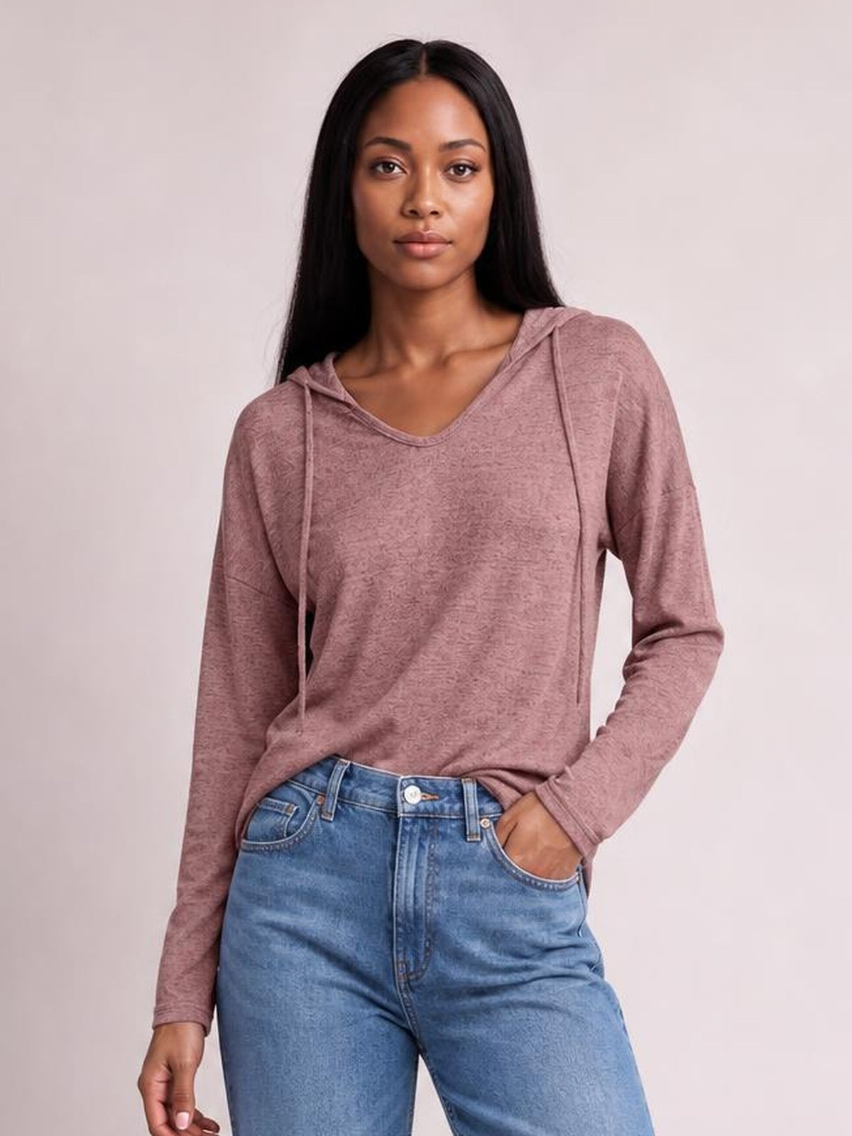 Model wears a mauve drawstring hooded T-shirt with dropped shoulders, long sleeves, a relaxed silhouette, and a slightly curved neckline.