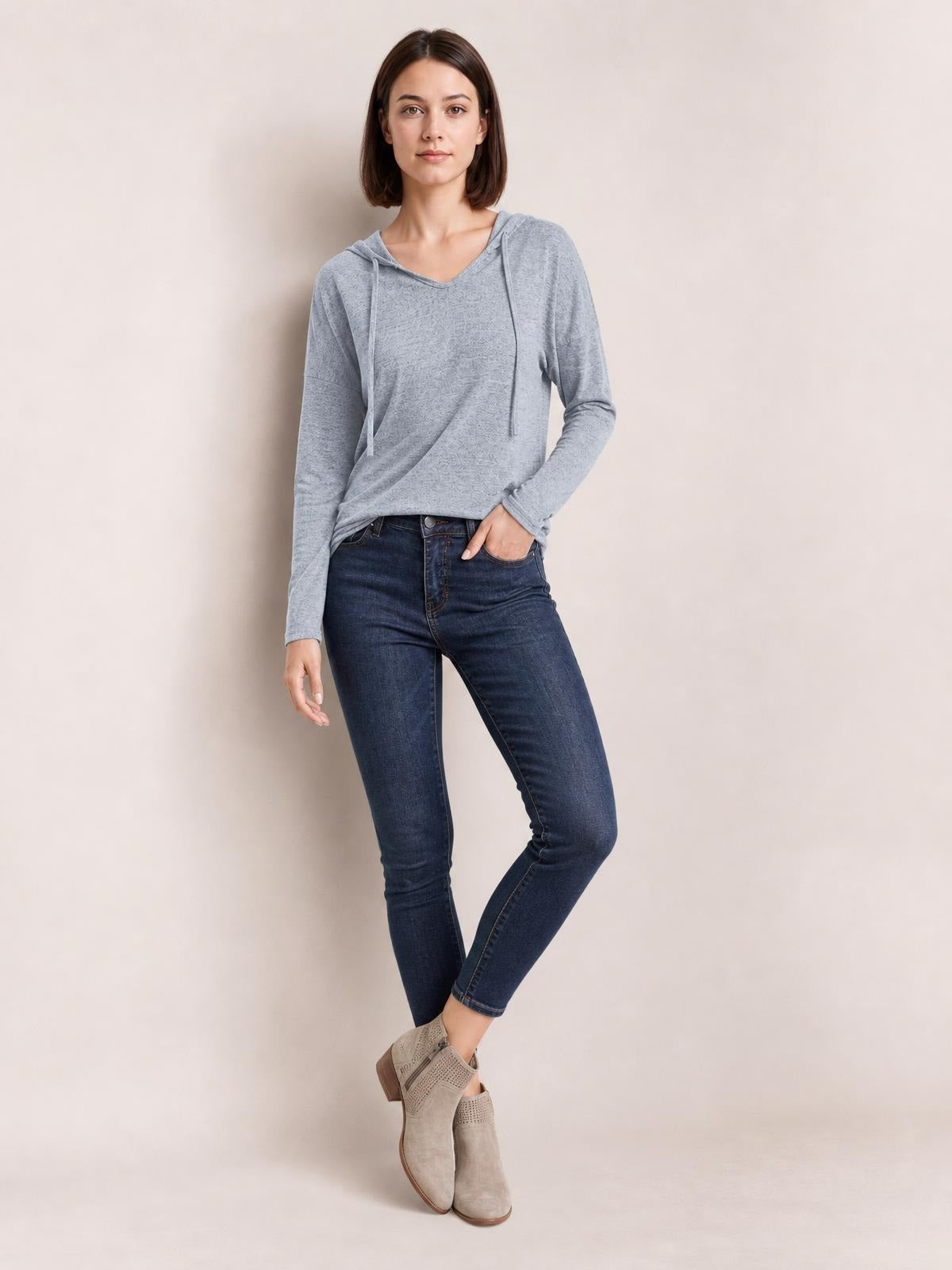 Model poses in a light gray drawstring hooded T-shirt with dropped shoulders, long sleeves, a relaxed drape, and slightly stretchy opaque construction.