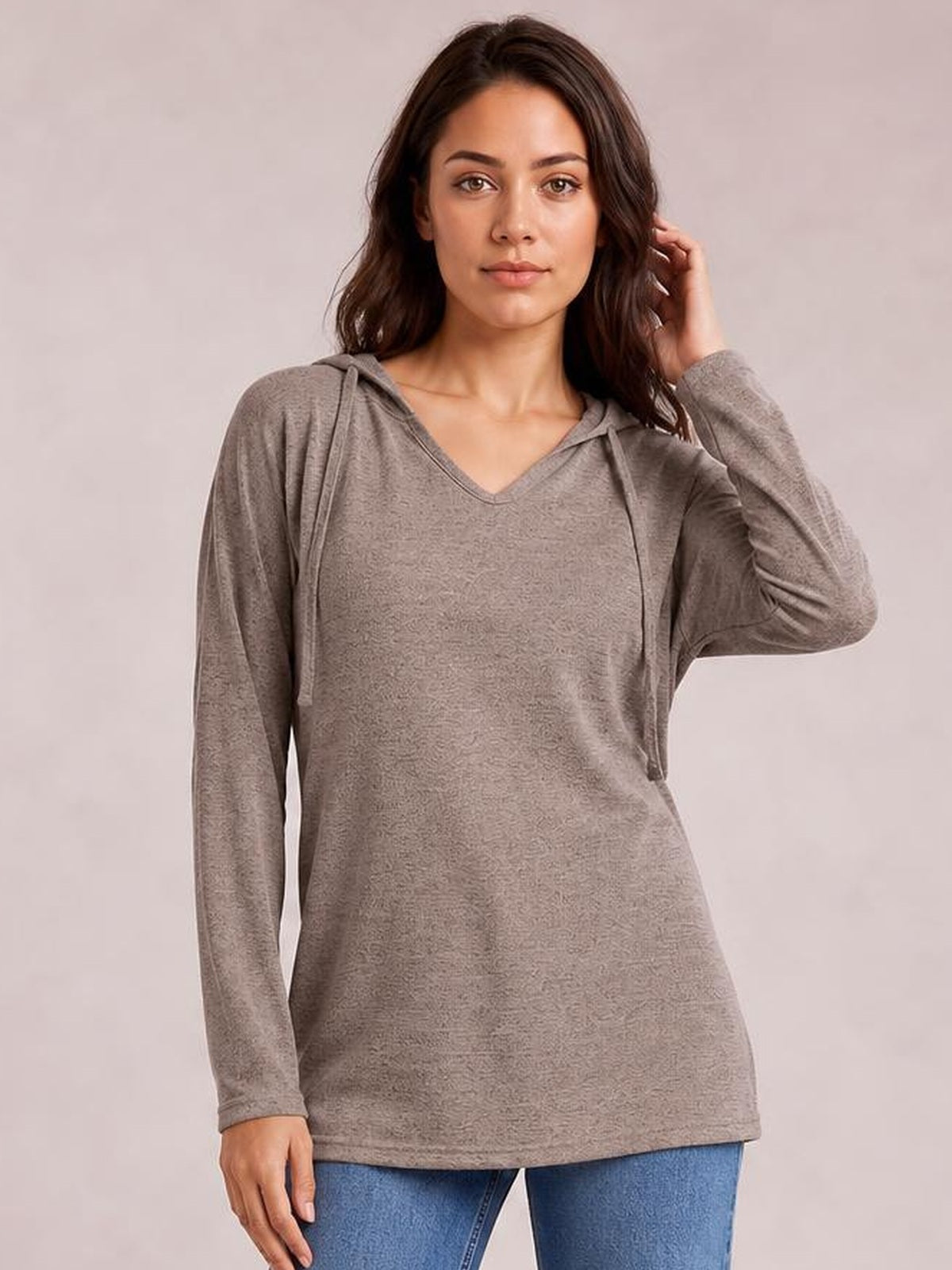 A model poses in a taupe drawstring hooded T-shirt with dropped shoulders, long sleeves, a relaxed straight silhouette, and V-shaped neckline.