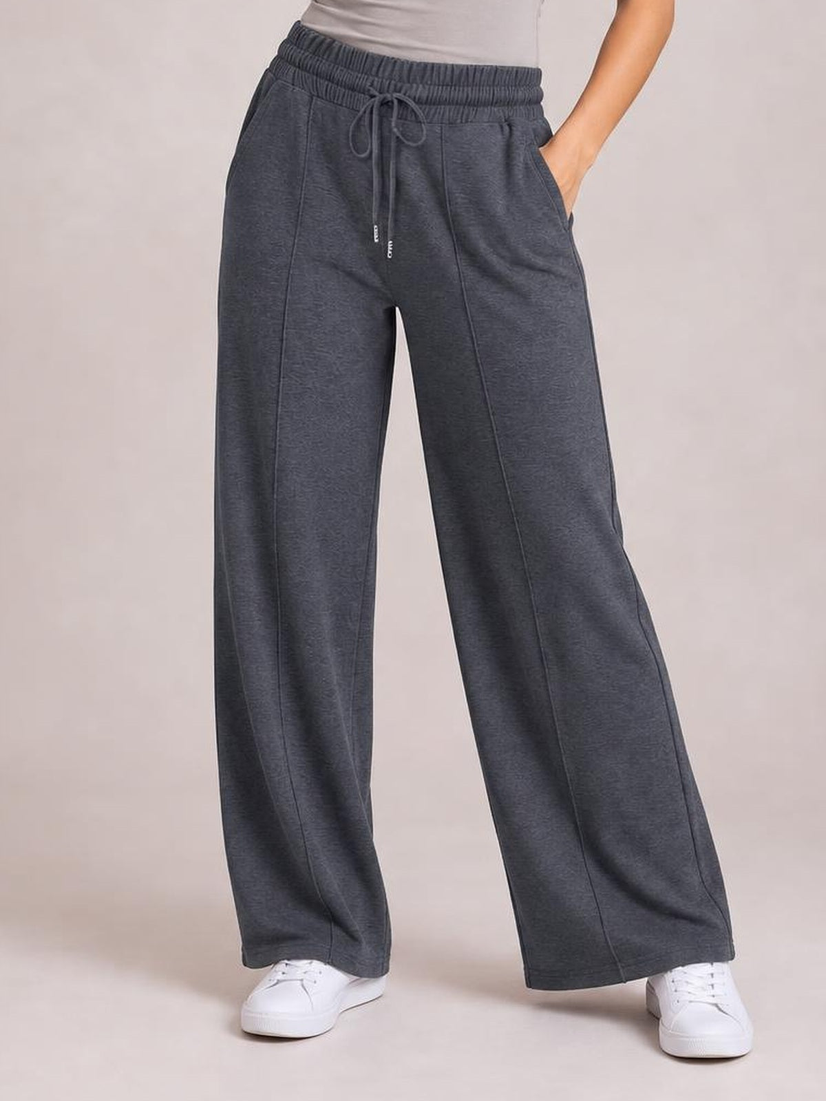 Model wearing dark gray drawstring elastic waist wide leg pants with side pockets, front seam detailing, and a relaxed flowy silhouette.