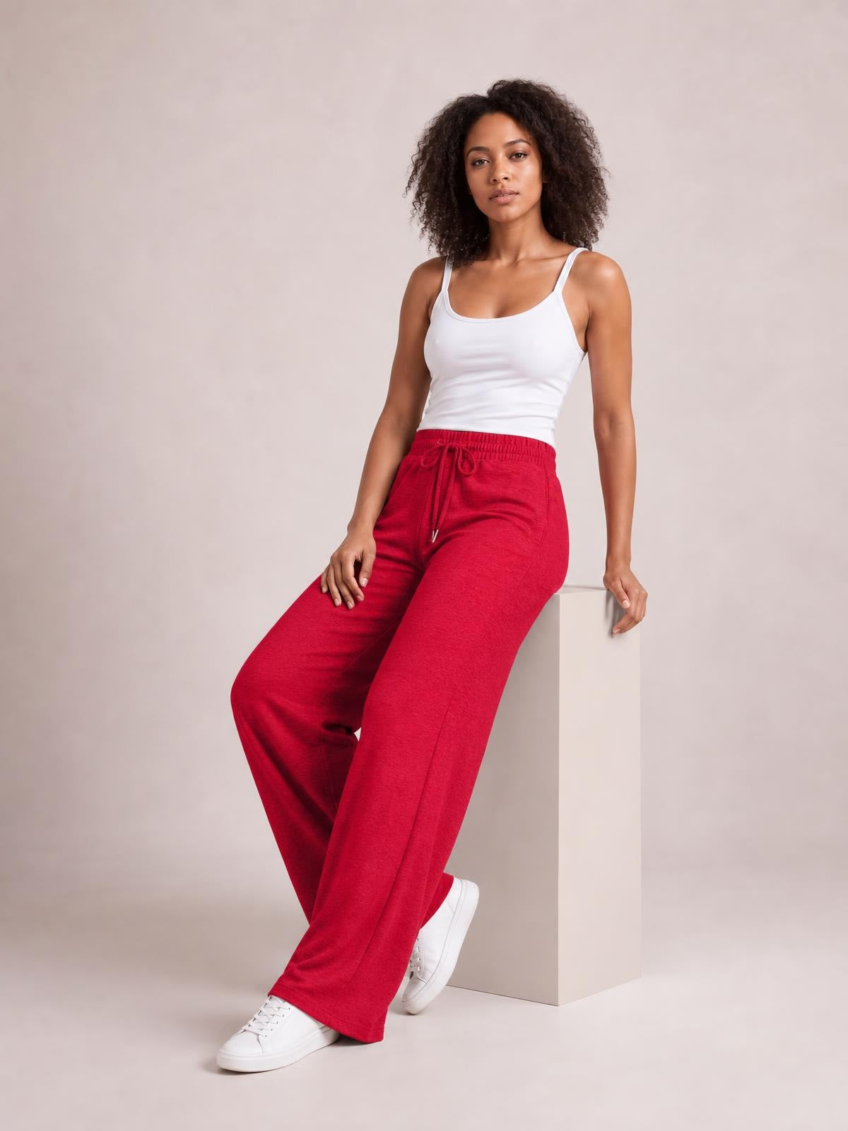 Model seated in bright red drawstring elastic waist wide leg pants, featuring a relaxed flowing silhouette and visible front pockets.