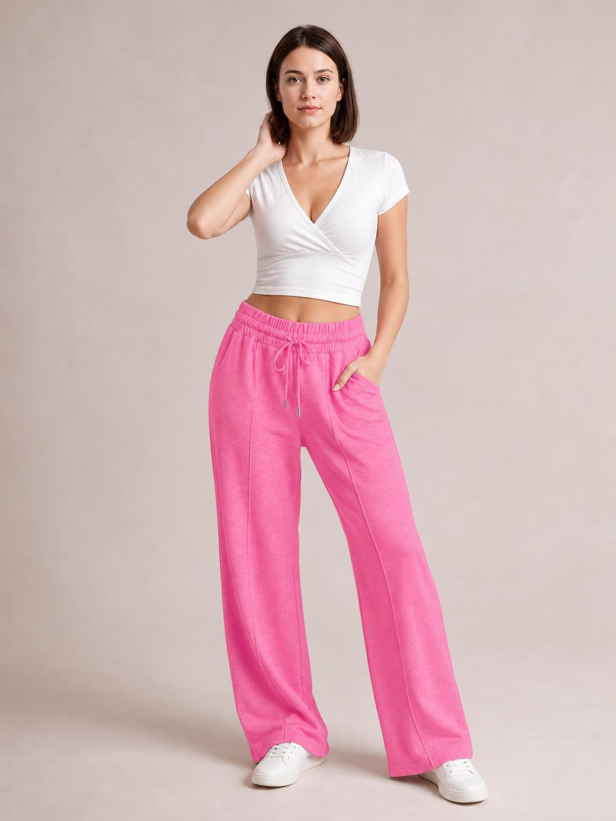 Model poses in bright pink drawstring elastic-waist wide-leg pants with front pockets, relaxed flowing legs, and a full-length silhouette.
