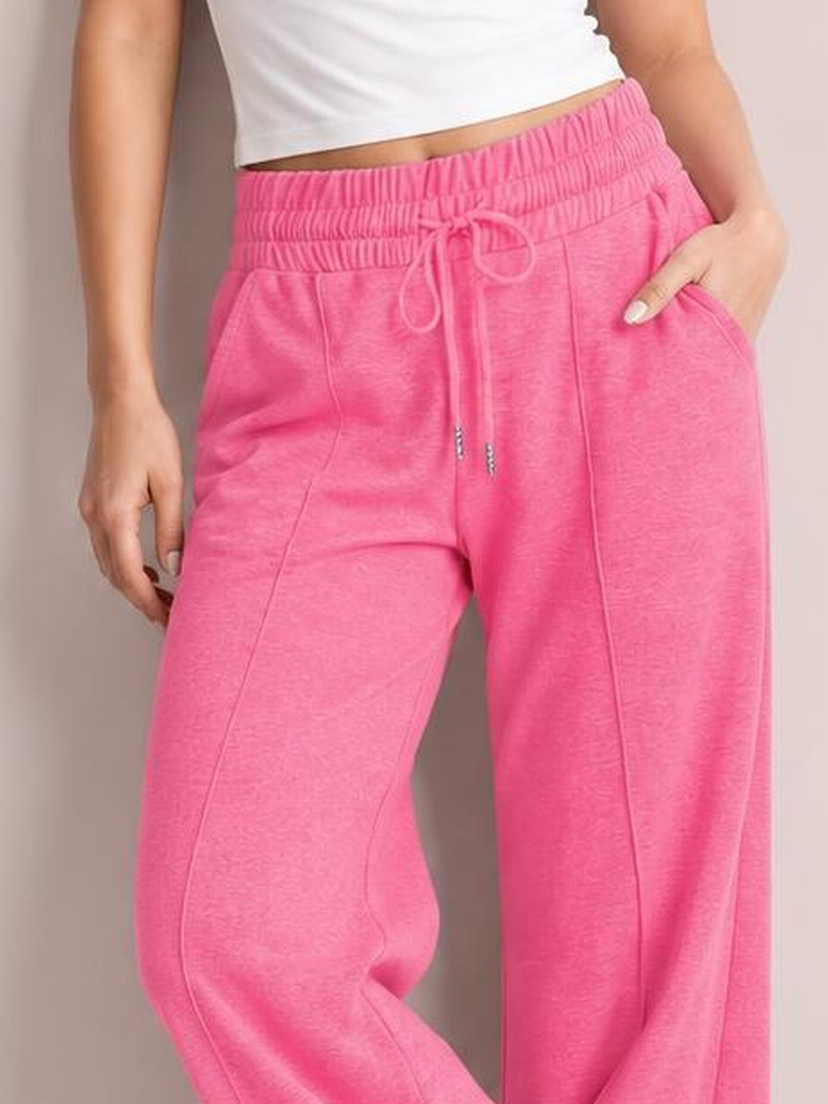 Model wearing bright pink drawstring elastic waist wide leg pants with visible pockets, gathered waistband, and relaxed flowy silhouette.