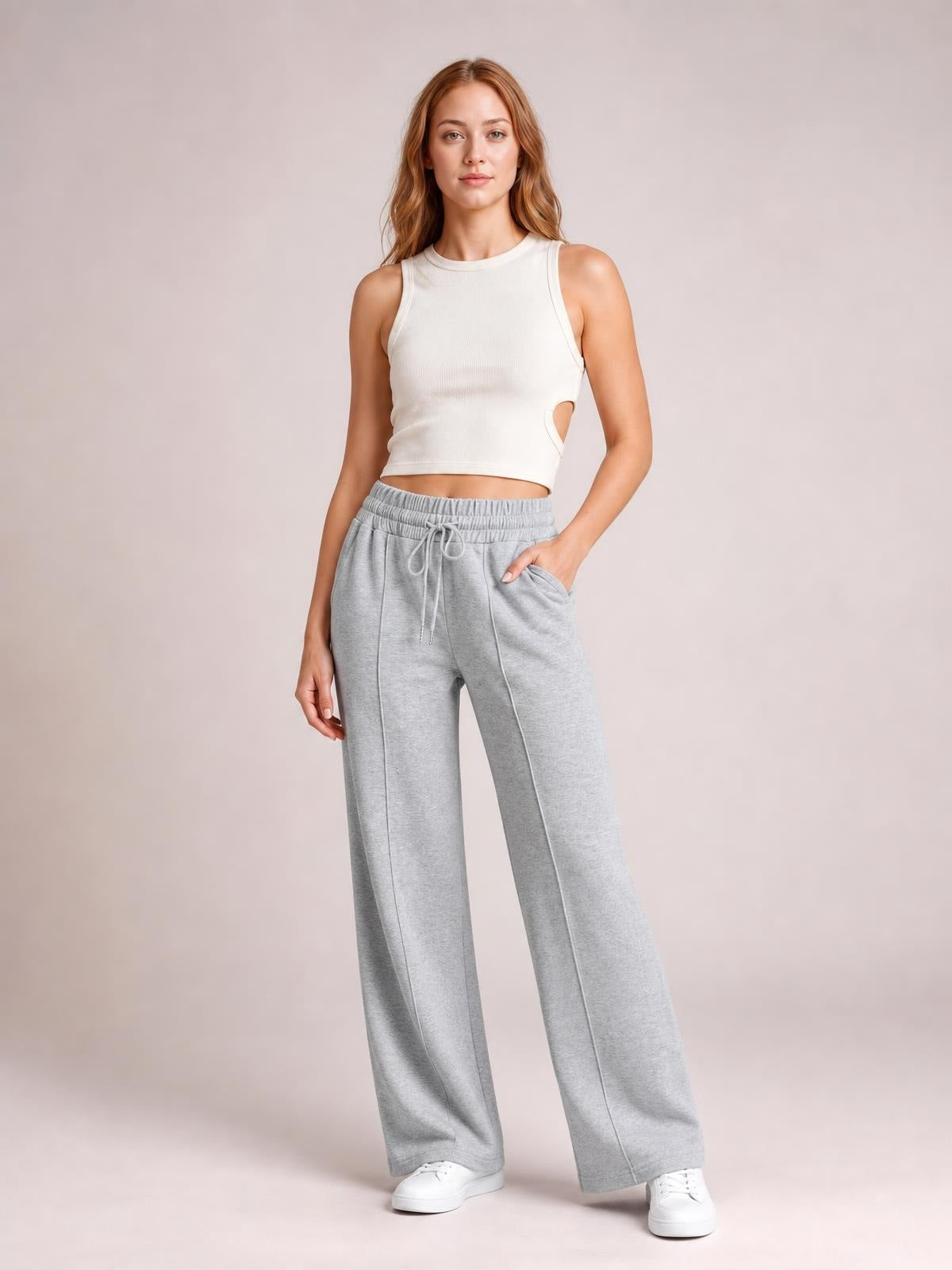 A model stands in light gray drawstring elastic waist wide leg pants with visible pockets, relaxed flowing silhouette, and a hand tucked into one pocket.