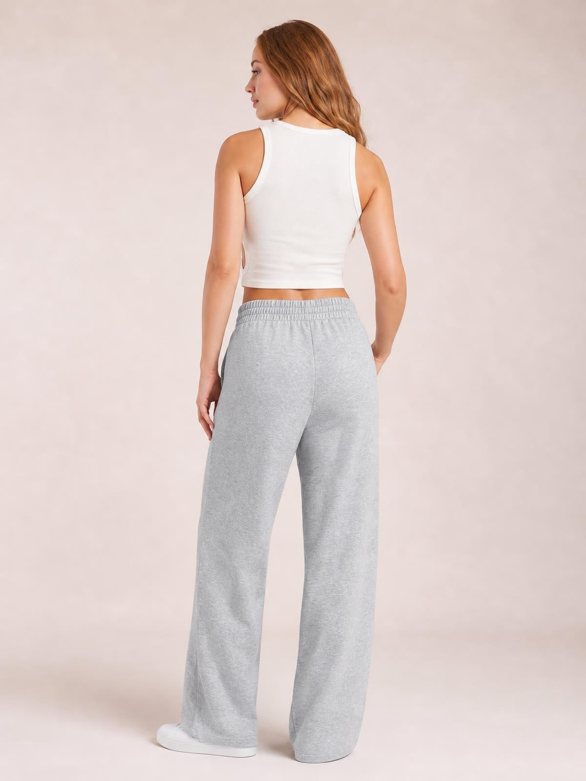 Model shown from behind wearing light gray drawstring elastic-waist wide-leg pants with a relaxed, flowy silhouette and visible side pockets.