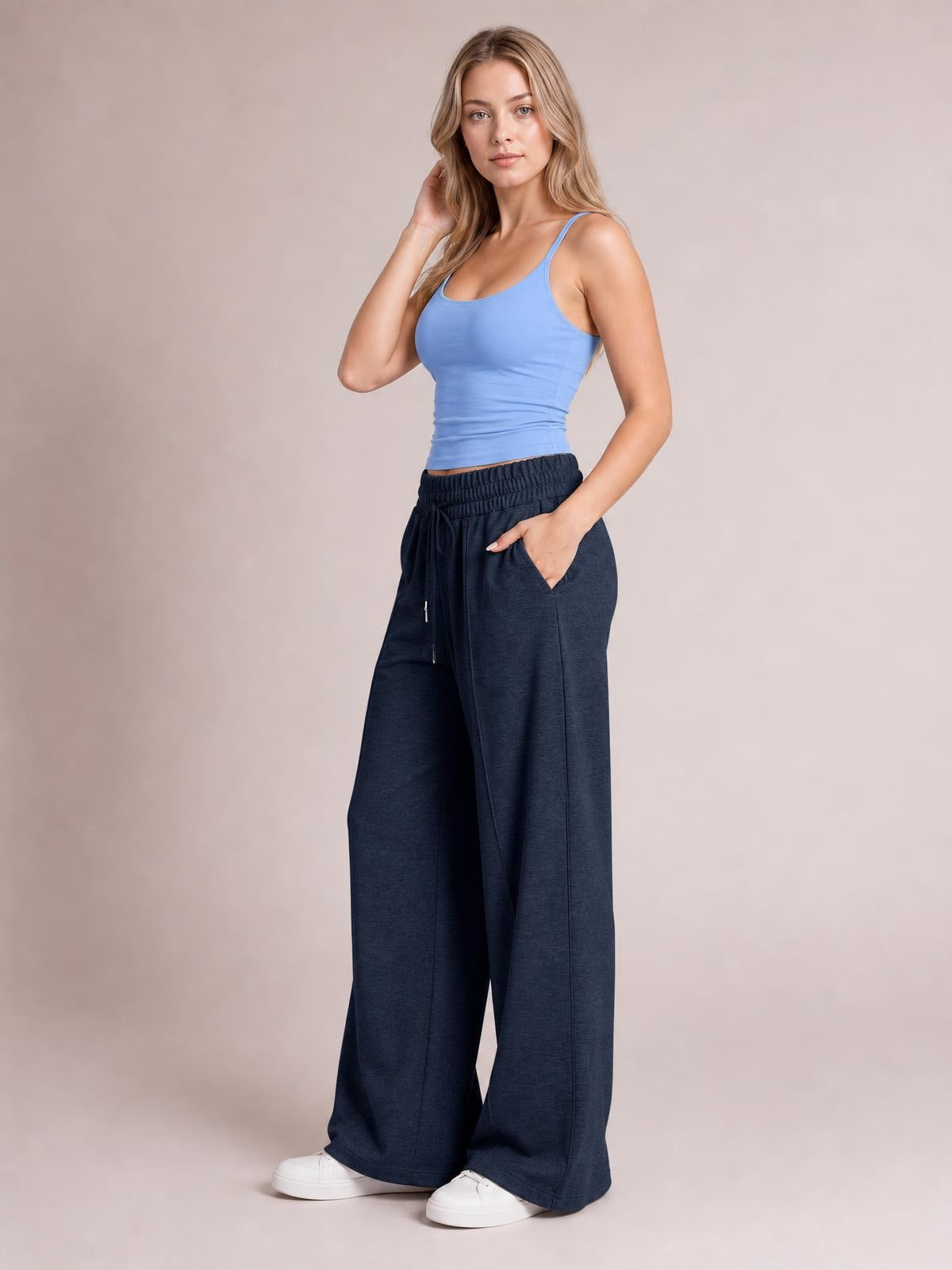 Model poses in navy drawstring elastic-waist wide-leg pants with a relaxed silhouette, visible side pockets, and one hand tucked into a pocket.