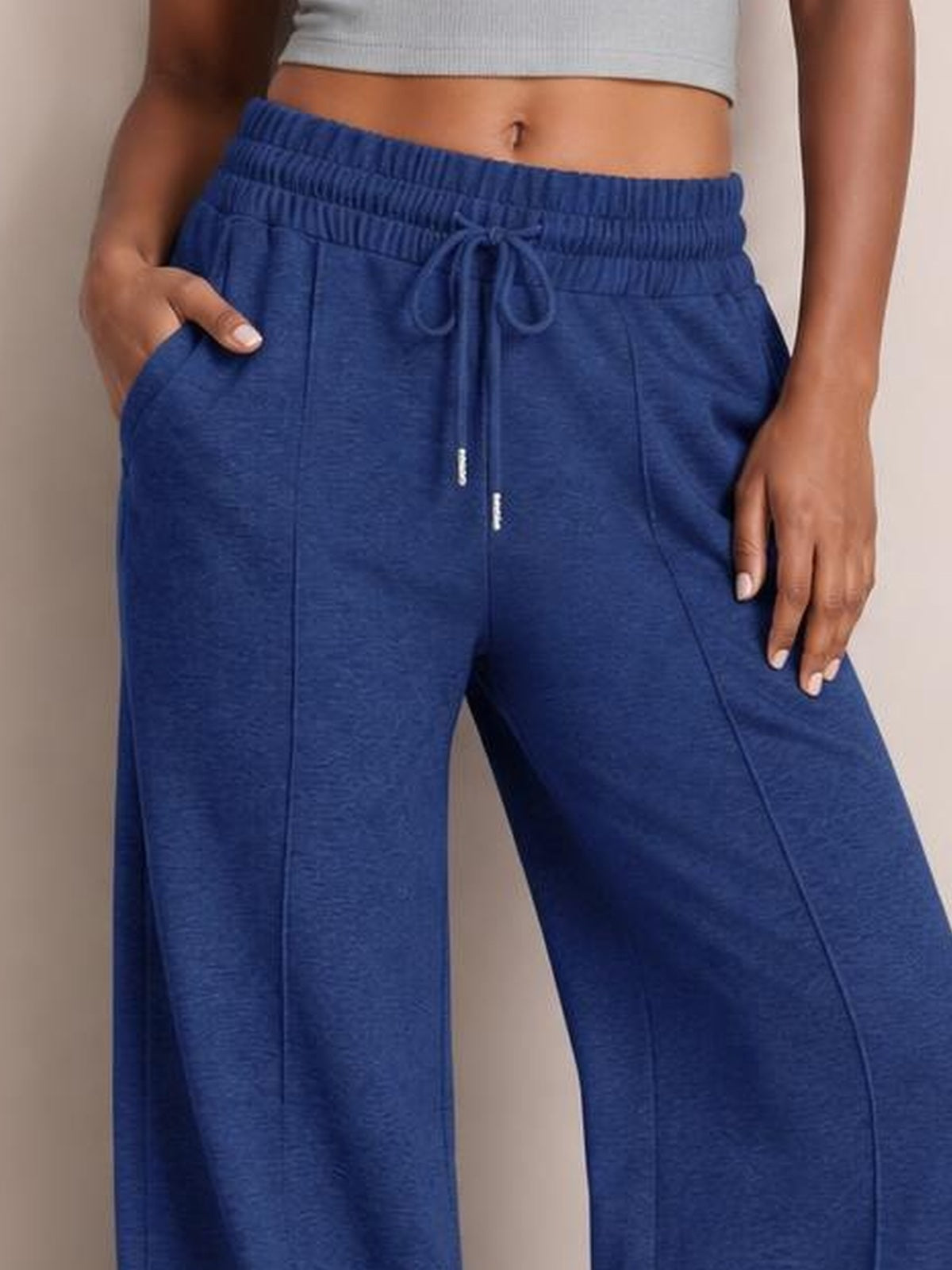 Model wearing blue drawstring elastic waist wide-leg pants with a relaxed silhouette, front pockets, and one hand tucked into a pocket.