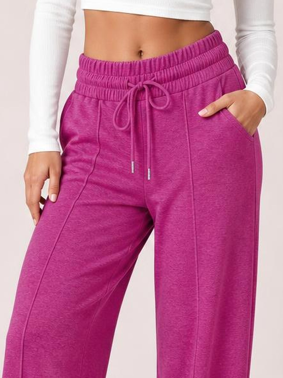 Model wearing fuchsia drawstring elastic waist wide leg pants with front pockets, relaxed flowy silhouette, and visible seam detailing.