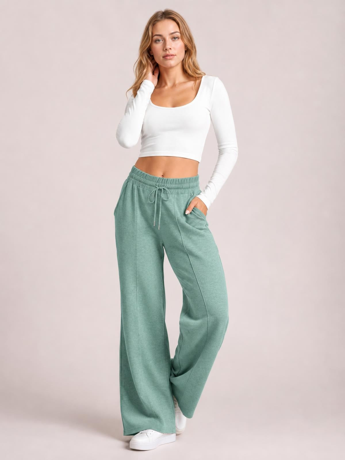 Model poses in sage green drawstring elastic waist wide leg pants with pockets and a relaxed, flowy silhouette.
