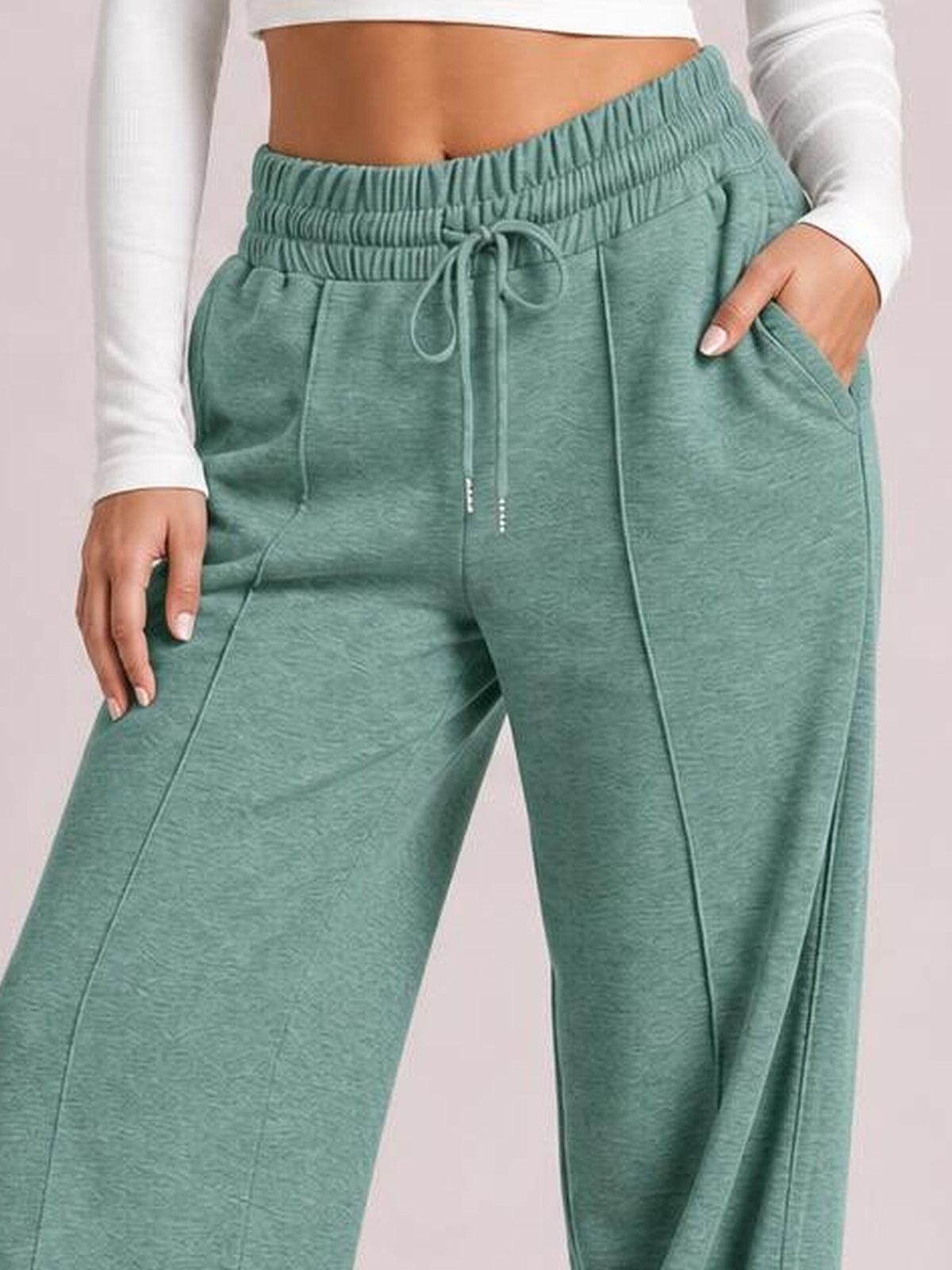 Model wears sage green drawstring elastic waist wide leg pants with a relaxed silhouette, front pockets, and visible seam construction.
