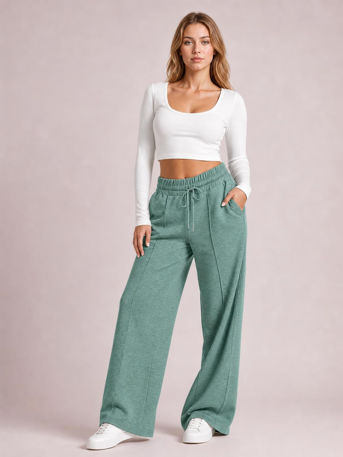 Model wearing sage green drawstring elastic waist wide leg pants with front pockets, seam details, and a relaxed flowy silhouette.