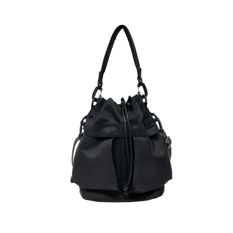 Medium black nylon bucket bag with a softly gathered drawstring opening, structured base, top handle, and adjustable side straps.